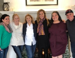 4 women and one man pose in front a of a fireplace while ushering in the holiday seeason 
