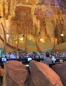 A waterfall with rock behind it falls behind a large bar. 