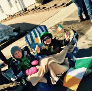Two young children, bundled in winter clothing, watch as the Irish Parade goes by. 