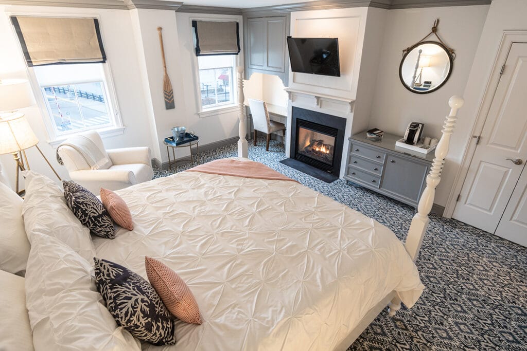 Overhead view of a white four-poster bed and gas fireplace in stonington, ct