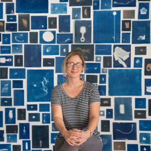 Artist, Elizabeth Ellenwood posing in front of cyano photography